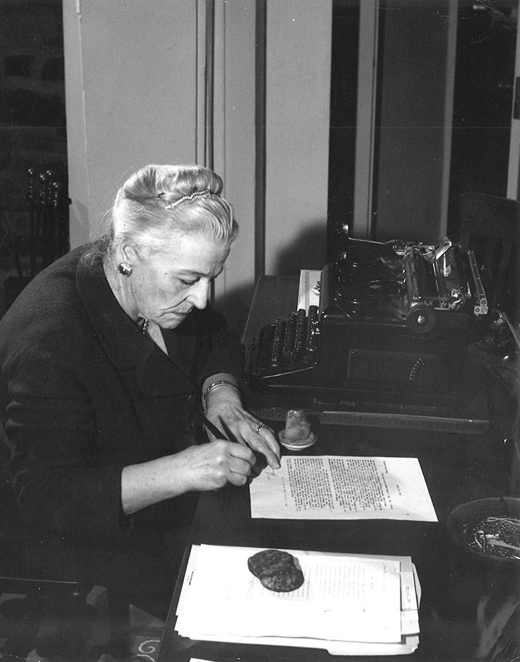 A black and white photo of Pearl S Buck sitting at her desk